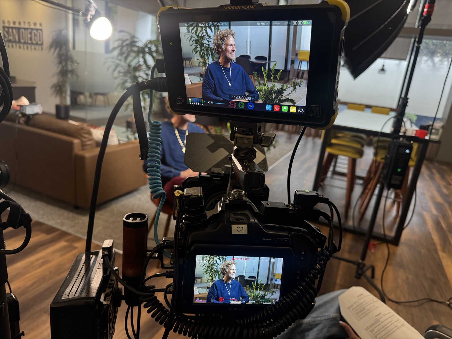Milan laughing on a production monitor, with Milan and the production equipment visible behind the scenes.